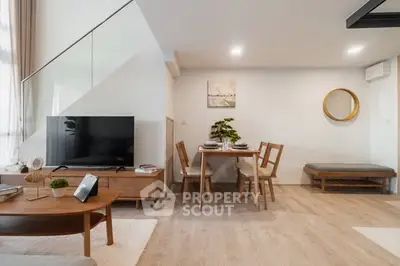 Modern living room with stylish furniture and dining area, featuring a sleek TV setup and elegant decor.