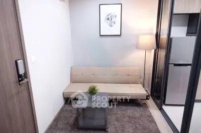 Modern living room with stylish decor and compact design, featuring a cozy sofa and sleek appliances.