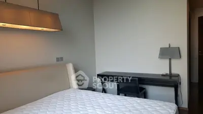 Modern bedroom with minimalist design and cozy lighting, featuring a comfortable bed and sleek desk.