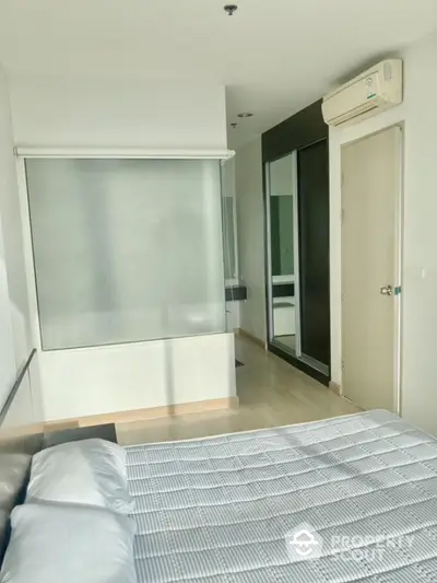 Modern bedroom with large window and mirrored closet doors in a bright apartment.