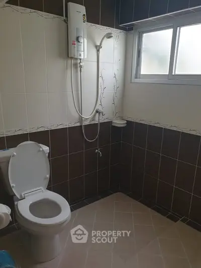 Modern bathroom with shower and toilet in a tiled interior.