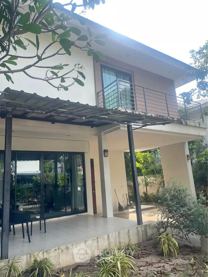 Modern two-story house with balcony and garden view, perfect for family living.