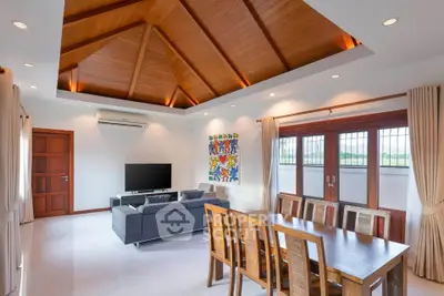 Spacious living room with wooden ceiling and modern furniture, perfect for family gatherings.