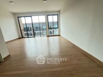 Spacious empty living room with large windows and wooden flooring