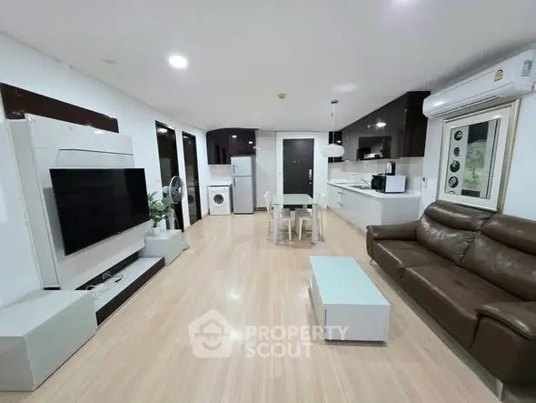 Spacious modern living room with open kitchen, featuring sleek appliances and stylish furniture.