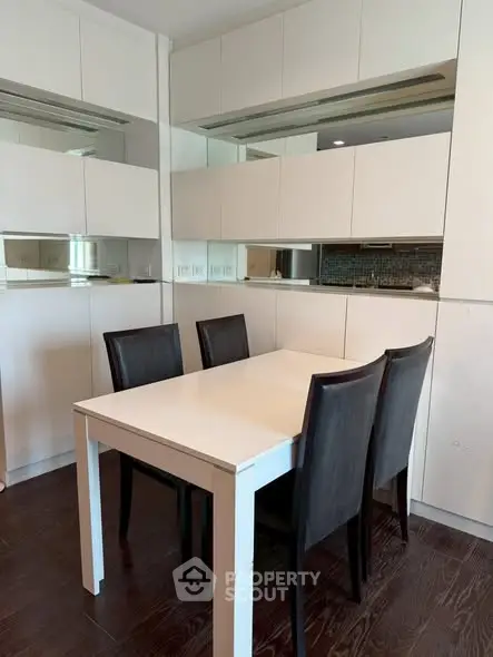 Modern dining area with sleek white table and dark chairs in a stylish apartment.