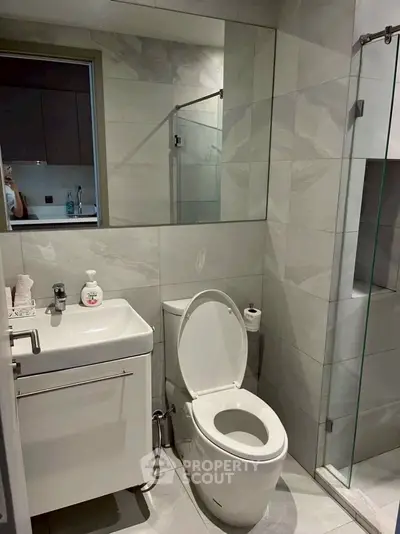 Modern bathroom with sleek fixtures and glass shower enclosure.