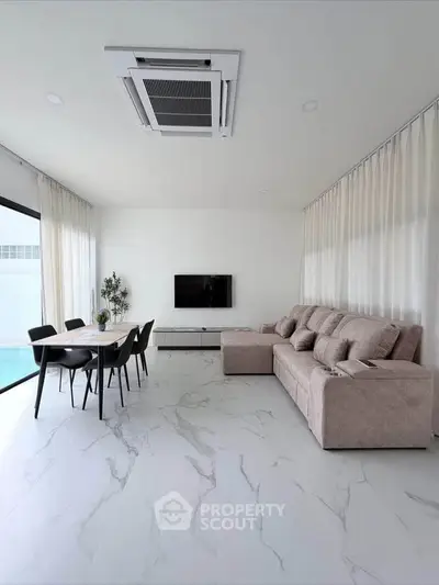 Modern living room with sleek marble flooring, stylish sofa, and dining area, featuring large windows for natural light.