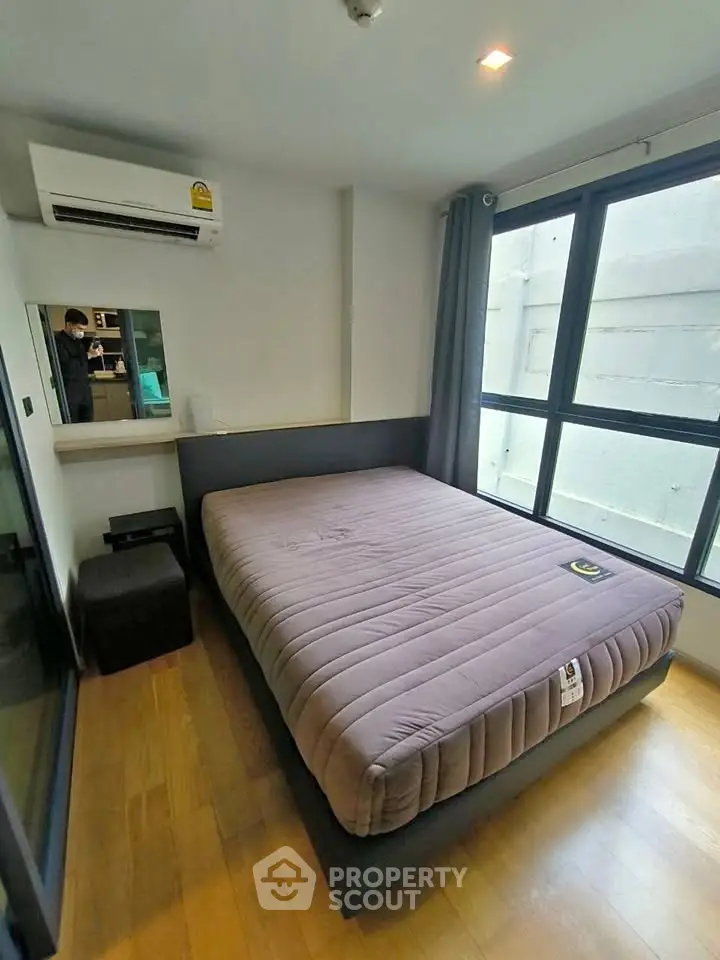 Cozy bedroom with large window and modern air conditioning unit, perfect for comfortable living.