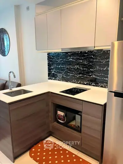 Modern kitchen with sleek cabinetry and black marble backsplash in a stylish apartment.