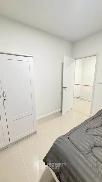Modern bedroom with sleek wardrobe and cozy bedding in a minimalist design.
