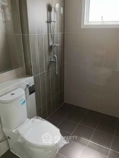 Modern bathroom with sleek tiles and a window for natural light.