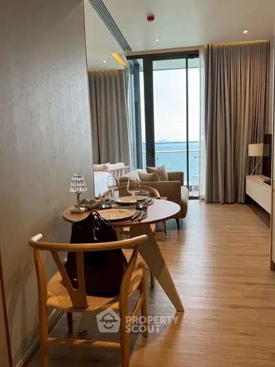 Modern open-plan living room with ocean view, featuring elegant dining setup and cozy seating area.