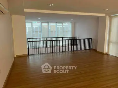 Spacious modern interior with wooden flooring and large windows, perfect for versatile living space.
