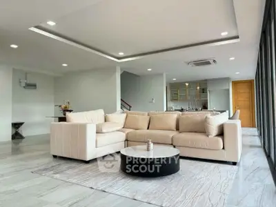 Spacious modern living room with elegant beige sofa and open kitchen layout, perfect for entertaining.