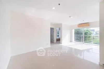 Bright and spacious living room with large windows and modern tile flooring.