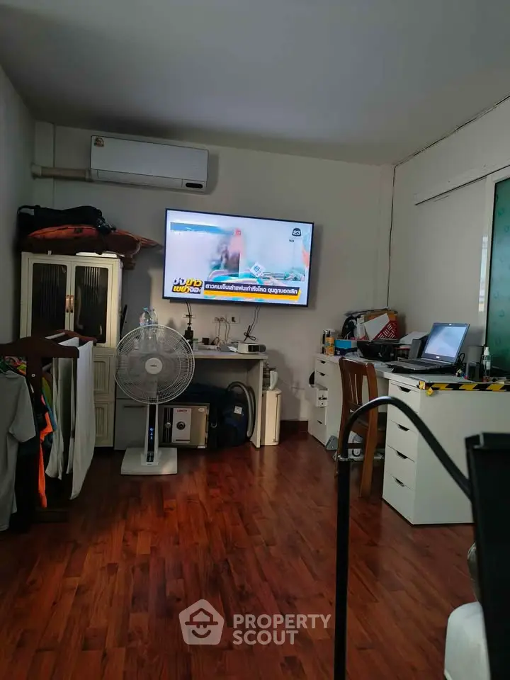Cozy living room with wooden flooring, wall-mounted TV, and modern furniture.