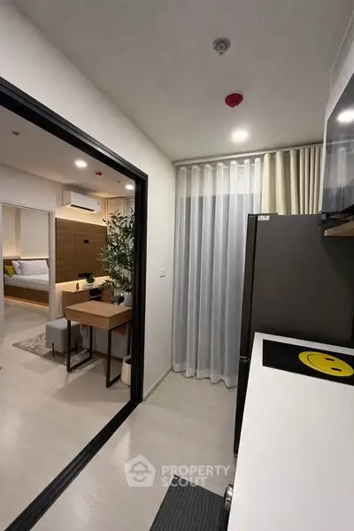 Modern apartment interior with open kitchen and cozy living area, featuring sleek design and natural lighting.