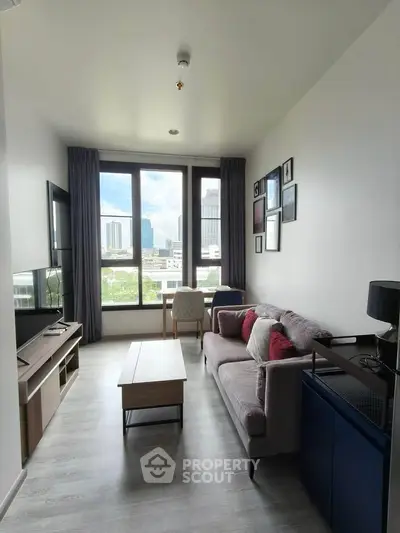 Modern living room with city view, featuring stylish furniture and large windows for natural light.