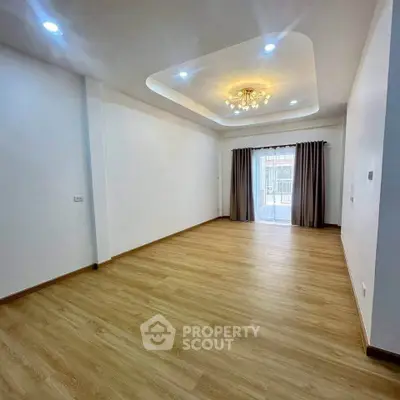 Spacious living room with elegant ceiling light and large window for natural light.