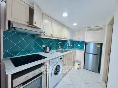 Modern kitchen with blue tile backsplash, built-in oven, and washing machine.