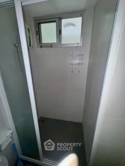 Compact bathroom with shower and window, ideal for small spaces.