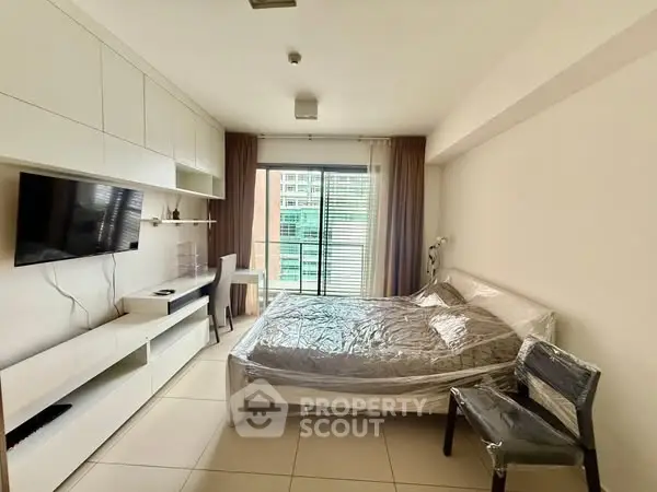 Modern bedroom with sleek built-in storage and large window view.