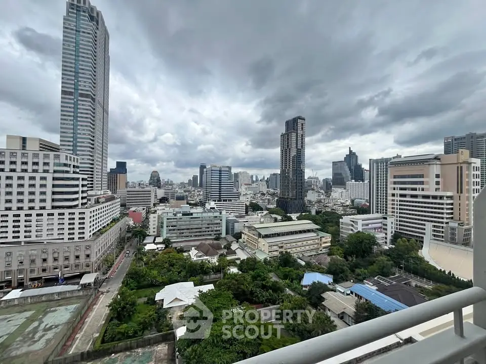 Stunning cityscape view from a high-rise balcony showcasing urban skyline and lush greenery.