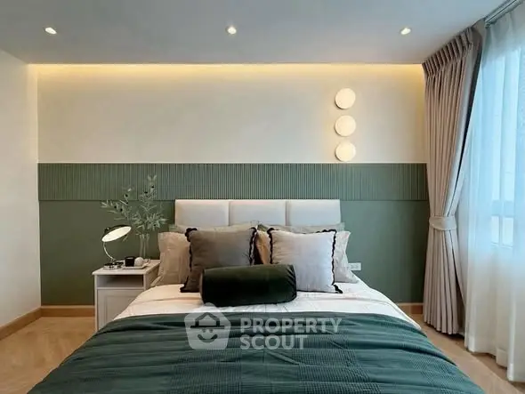 Elegant bedroom with modern decor and natural light, featuring stylish green accents and cozy ambiance.
