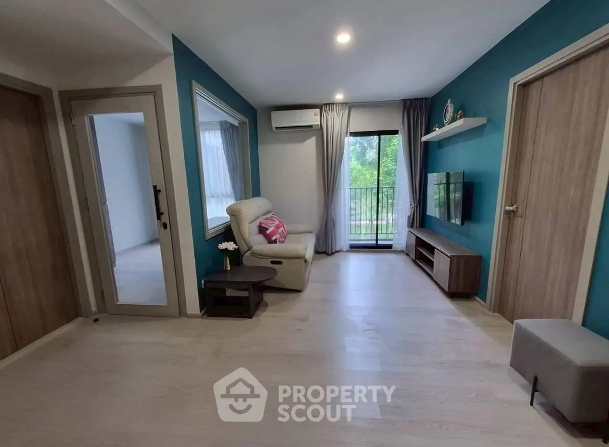Modern living room with balcony view, featuring sleek furniture and vibrant blue accent wall.