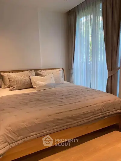 Cozy bedroom with large windows and elegant curtains, featuring a comfortable bed and stylish decor.