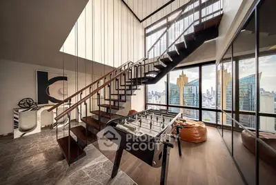 Luxurious penthouse with modern staircase and panoramic city views, featuring a stylish foosball table and chic decor.