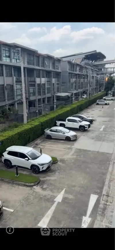 Modern residential building with parking area and greenery, showcasing urban living convenience.