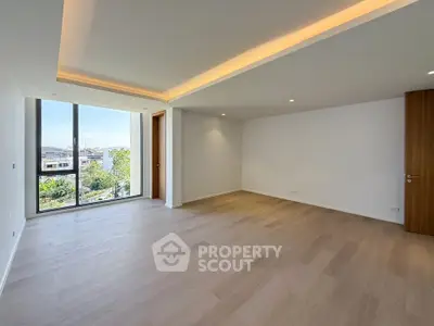 Spacious modern living room with large windows and wooden flooring, offering abundant natural light.