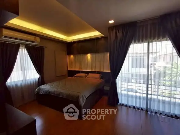 Luxurious bedroom with modern lighting and large windows offering natural light.