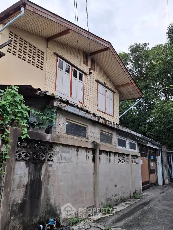 Charming two-story home with rustic exterior and lush greenery, perfect for renovation enthusiasts.