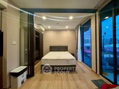 Spacious bedroom with large windows offering city views, featuring a comfortable bed and modern decor.