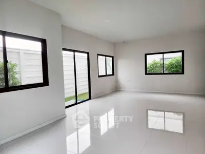 Spacious modern living room with large windows and glossy white tiles