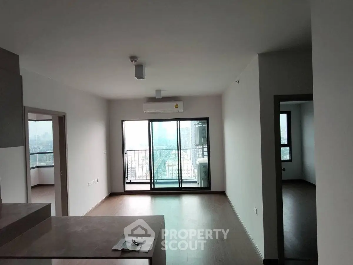 Spacious modern apartment with large windows and city view, featuring open layout and sleek flooring.