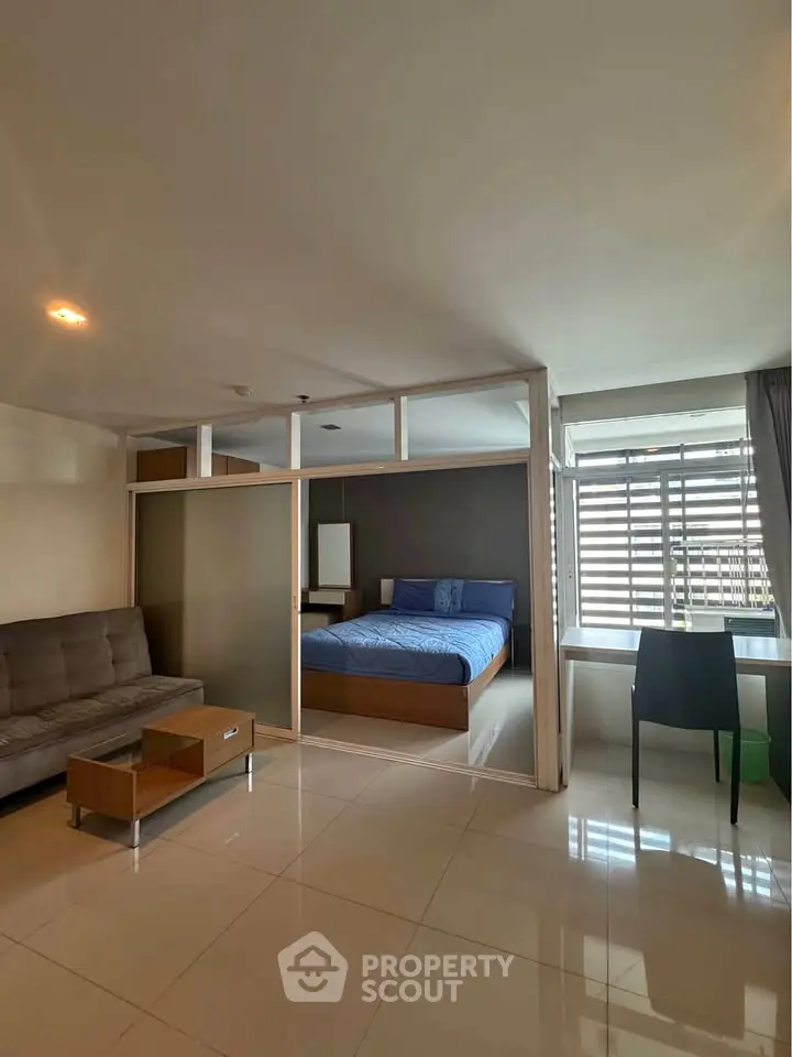 Modern studio apartment with glass partition, featuring a cozy bedroom and stylish living area.