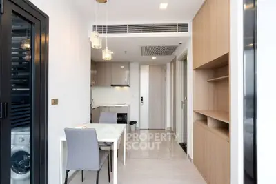 Modern apartment interior with sleek kitchen and dining area, featuring contemporary furniture and stylish lighting.