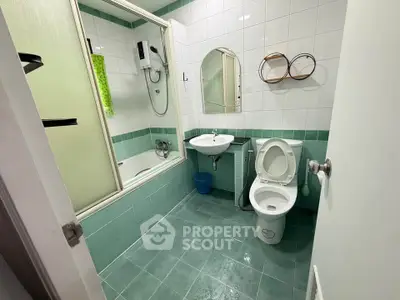 Modern bathroom with green tiles, bathtub, and shower in a stylish real estate property.
