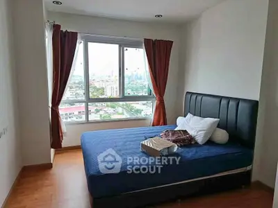 Cozy bedroom with city view, featuring a comfortable bed and large window for natural light.