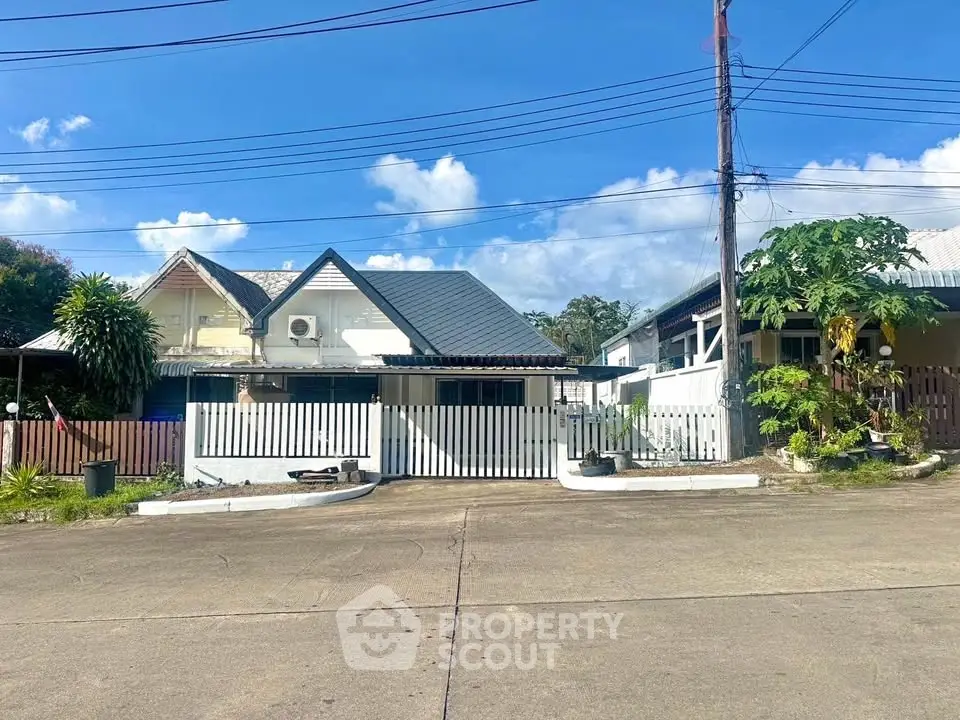 Charming suburban house with a spacious driveway and lush greenery under a clear blue sky.
