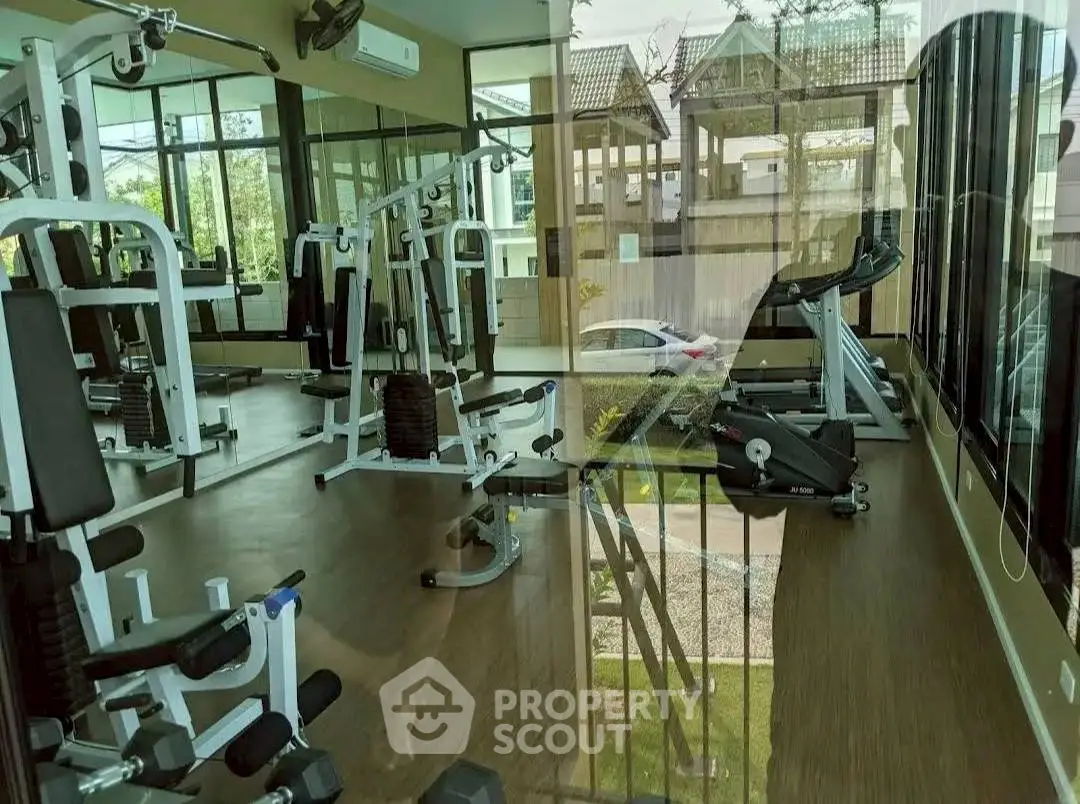 Modern gym with state-of-the-art equipment and large windows offering natural light and outdoor views.