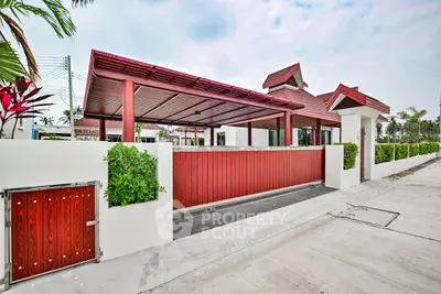 Charming red-roofed house with lush greenery and modern design in a serene neighborhood.