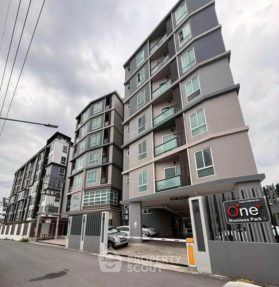 Modern multi-story apartment building with sleek design and secure gated entrance.