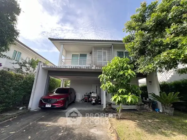 Charming two-story house with carport and lush greenery in a serene neighborhood.