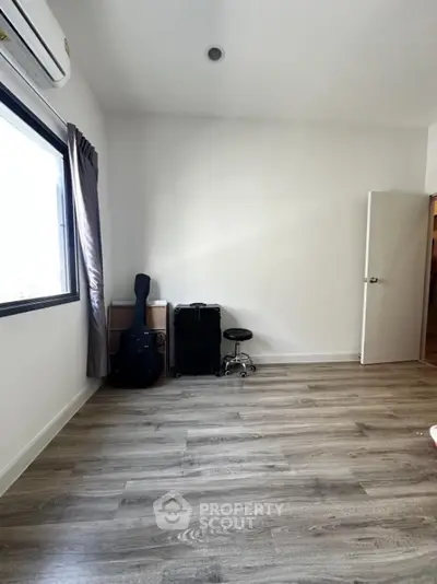 Spacious room with wooden flooring and natural light, ideal for creative setup.