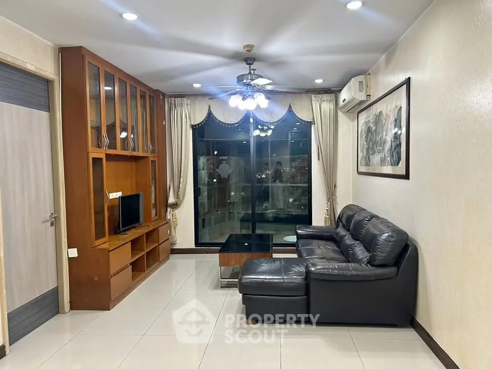 Spacious living room with leather sofa and large window offering city views.
